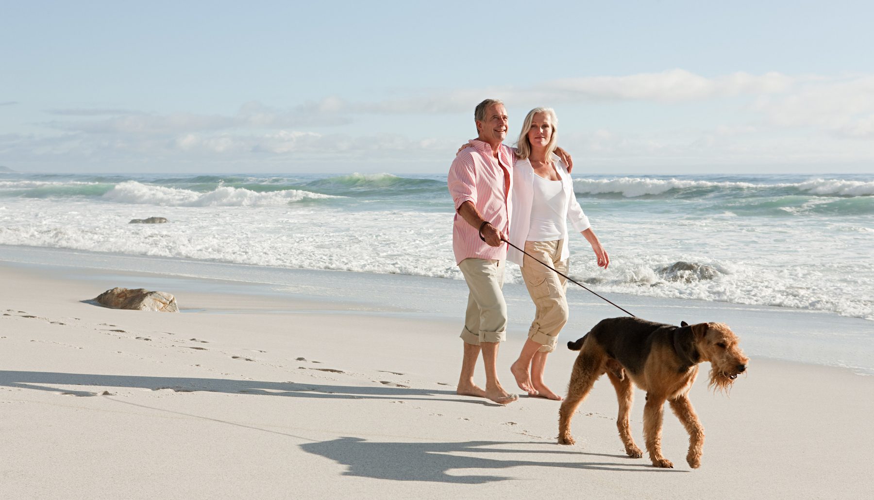 Couple walking dog by the sea