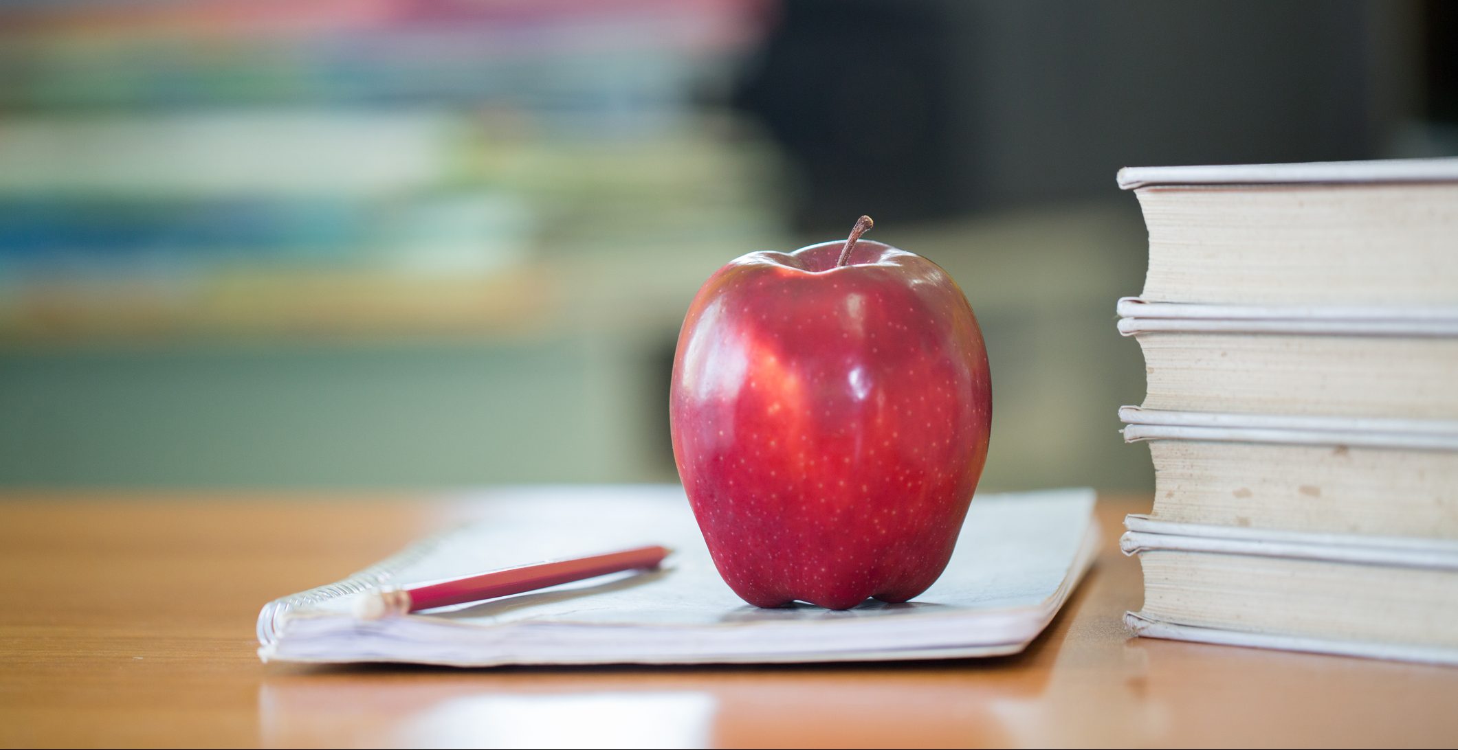 School teacher's desk with stack of books and apple, Educational concept.